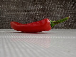 Shiny bright red chili pepper isolated on a dark background. Useful for food and spices related...
