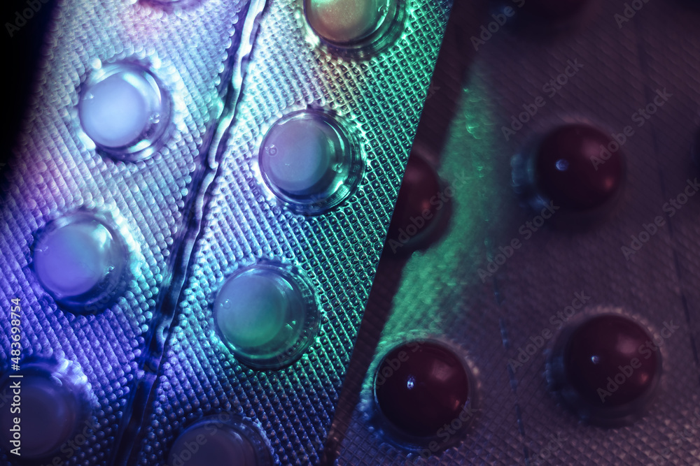 Poster Pills or drugs in a package under neon light on a dark background pattern for design..