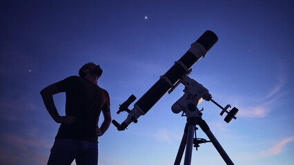 Silhouette of a man, telescope under the starry skies.