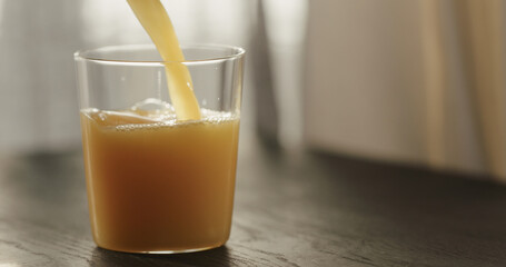 pour orange juice in tumbler glass on black wood table with copy space