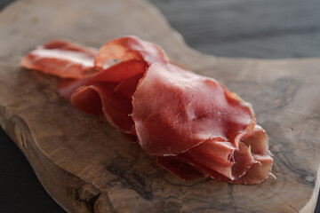 bresaola slices on olive wood board