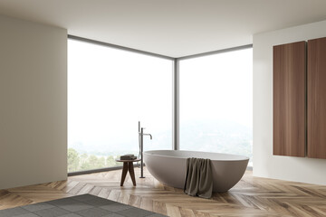 Light bathroom interior with bathtub and table with towels, window