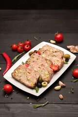 Sliced Traditional French terrine covered with bacon on dark wooden background