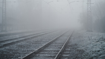 Several train rails ending in fog, railway tracks during a cold autumn morning