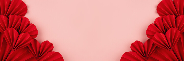 Valentines day banner - beautiful red paper ribbed hearts in simple origami style on pastel pink color as sideways border, frame, copy space, top view.