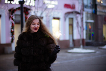 Fototapeta premium portrait of a girl in winter in a fur coat with sparkler