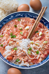 Close-up of chinese tomato egg-drop soup with rice noodles, vertical shot, selective focus
