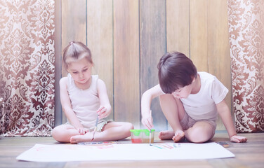 Obraz na płótnie Canvas Little children paint on a large sheet of paper