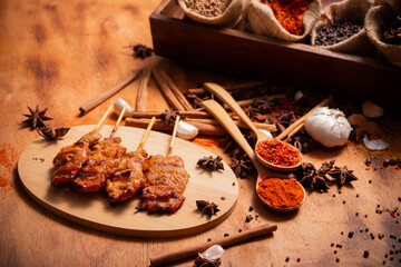 Thai style Grilled Pork Skewers with herb on wooden plate with various herbs.
