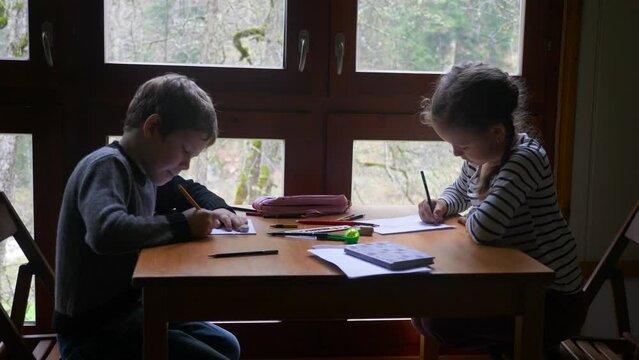 Two caucasian children are drawing near the window. Brother and sister are spending time together. High quality 4k footage
