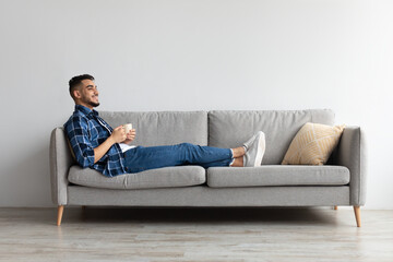 Man having rest at home on the couch, drinking coffee