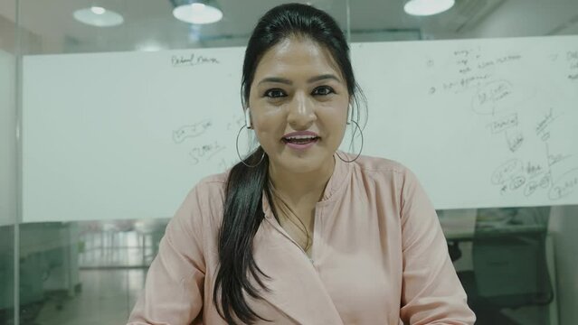 Young indian business woman speaks looks at camera works from office room.Female worker, online applicant talks during remote job interview video chat, conference call, web training concept.