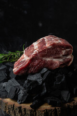 A piece of raw pork on the coals close-up