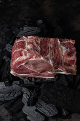 A piece of raw pork on the coals close-up