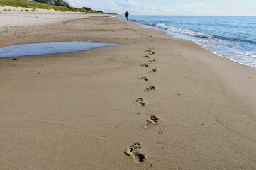 Footprints on the sea sand. Hike along the sea. Baltic coast and quiet sea.