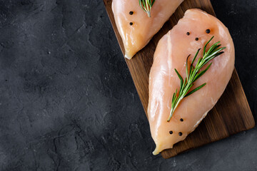 raw fresh chicken fillet with rosemary and spices on a dark background