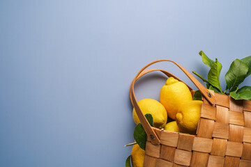 fresh lemons with green leaves in Cotton eco bag on blue background, flat lay. Eco friendly zero...