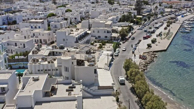Parikia Paros Greece Aerial v3 birds eye view drone flying along the coastal road christoi konstavtopoiloi and waterfront promenade capturing greek style white facade buildings - September 2021