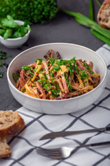 Sliced meat salad with cheese, mushrooms, greens vegetables and seasoned with sauce. Healthy lunch menu. Restaurant food. Grey background. Studio shot.