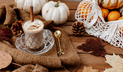 Obraz na płótnie Canvas Cup of Pumpkin Spice Latte and Fall Decor from fresh pumpkins. Traditional Coffee Drink for Autumn Holidays, cozy, hygge, comfortable