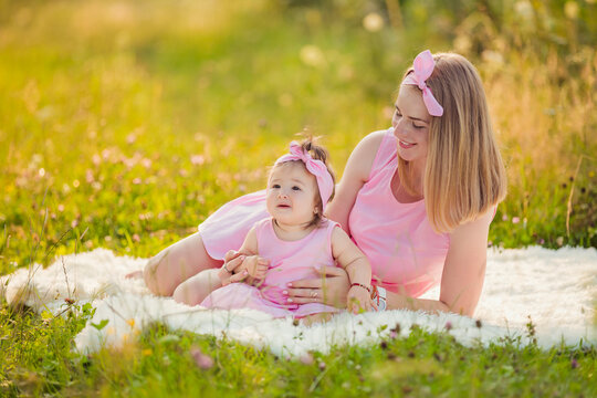 mother and daughter are sitting on a blanket in the summer garden