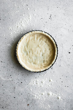 An unbaked tart shell on a stone surface