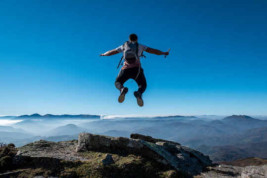 Jovem rapaz num salto de alegria no alto das montanhas La Rhune no Pa&iacute;s Basco, Fran&ccedil;a