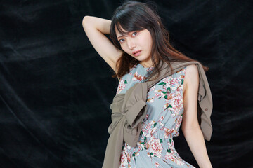 黒背景の前でポーズする袖なしワンピースのセクシーな日本人女性