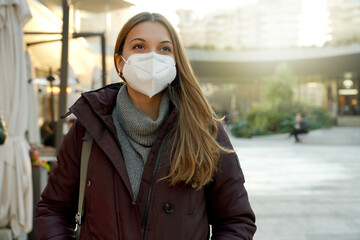 Happy young woman using medical face mask over city background looking to the side and staring away...