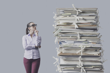 Frustrated businesswoman staring at a huge pile of paperwork