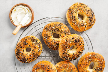 Fresh baked sourdough New York style bagels with cream cheese on light gray table.	