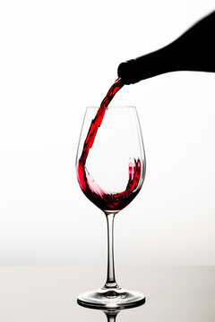 Glass of red wine. Red wine poured into the glass photographed in motion. Dynamic and modern image