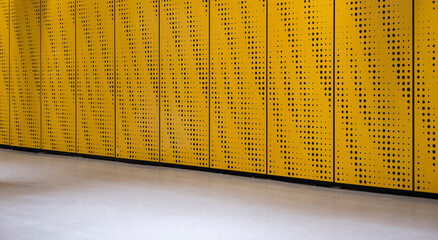 Perforated metal wall background, front view. Yellow metal background with lines and dots.