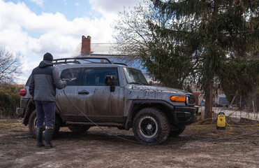 Obraz premium a man washes his dirty car in the yard of his house