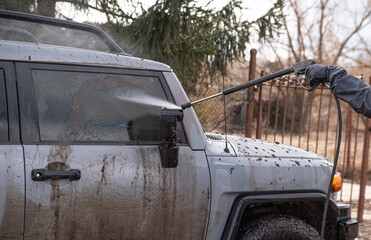a man washes his dirty car in the yard of his house
