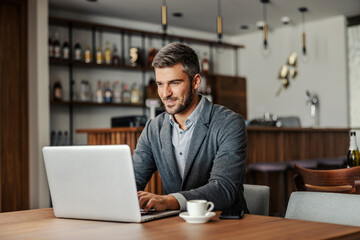 A businessman is sitting in a working friendly cafe and working on project.