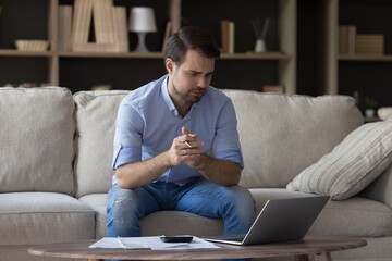 Frustrated unhappy young man looking at laptop screen, feeling stressed getting bank loan rejection...