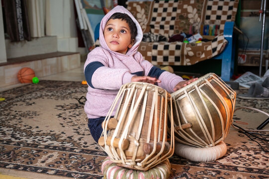 a small child trying to learning to play the tabla .