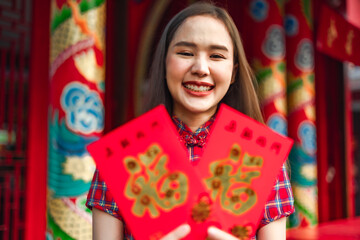 Beautiful Asian woman wearing a traditional red cheongsam on Chinese New Year.Hand holding red envelope or Ang pao with Chinese character means happiness or good fortune.