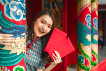 Beautiful Asian woman wearing a traditional red cheongsam on Chinese New Year.Hand holding red...