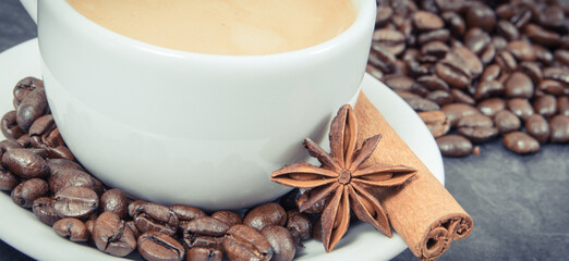 Coffee in white cup and roasted dark coffee beans with seasonings