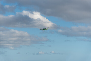 Fototapeta na wymiar Avión de color blanco y verde atravesando un cielo azul con alguna nube en Lanzarote, Islas Canarias.