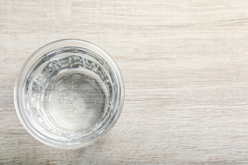 Glass of soda water on white wooden table, top view. Space for text