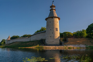Fototapeta na wymiar View of the wall of the Pskov Kremlin and High (Vysokaya) tower on the bank of the Pskova River on a sunny summer day, Pskov, Russia