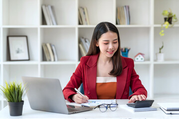 Confident young Asian businesswoman sitting working at her workplace at modern office.