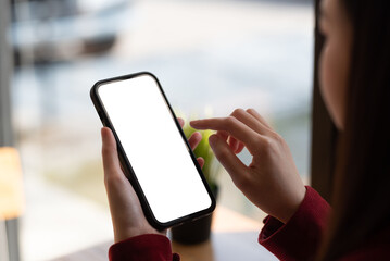 Woman sitting using a smartphone blank white screen at the office. Mock up.