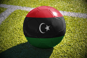 football ball with the national flag of libya lies on the green field