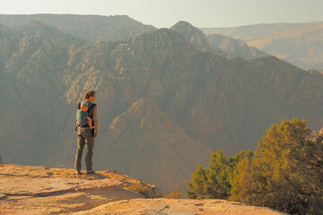 A beautiful young mom with her infant daughter in a baby carrier in the mountains. Wadi Dana,...