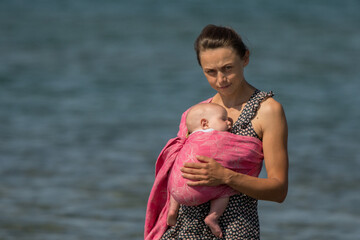 A beautiful young mom with an infant daughter in a wrap.