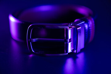  black leather belt on a black table in the dark in the rgb colour light. accessories store for men
